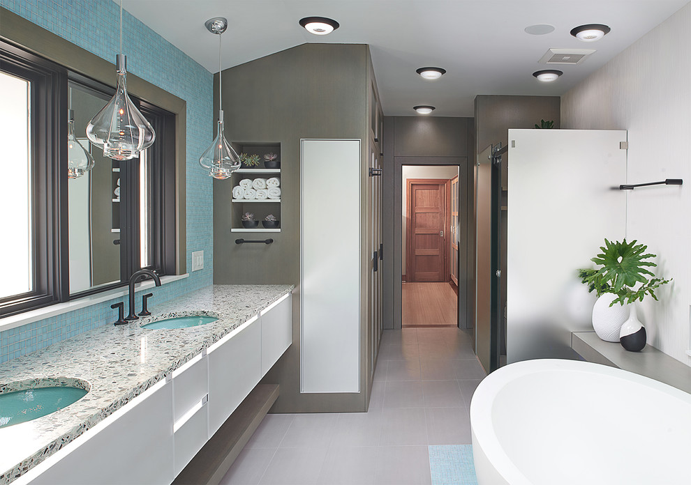 Inspiration för stora moderna en-suite badrum, med luckor med glaspanel, vita skåp, ett fristående badkar, en kantlös dusch, en bidé, vit kakel, keramikplattor, klinkergolv i porslin, ett undermonterad handfat, bänkskiva i återvunnet glas, grått golv och dusch med gångjärnsdörr