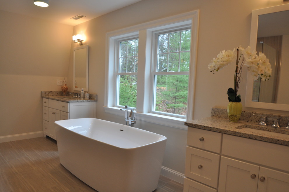 Expansive modern ensuite bathroom in Boston with a submerged sink, shaker cabinets, white cabinets, granite worktops, a freestanding bath, a corner shower, grey tiles, ceramic tiles and ceramic flooring.