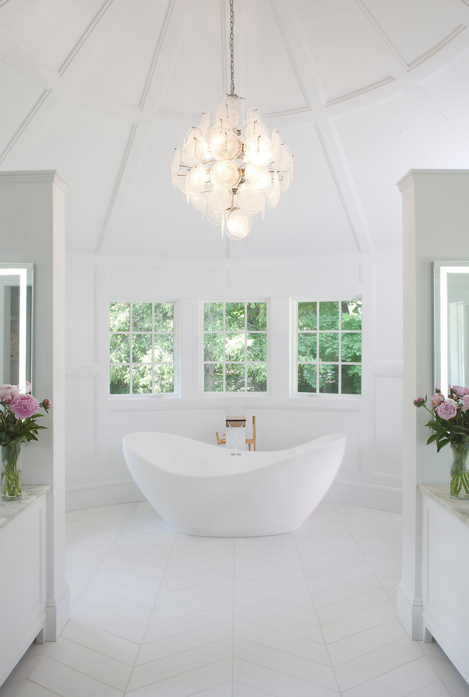 Стильный дизайн: огромная главная ванная комната в стиле неоклассика (современная классика) с фасадами с утопленной филенкой, белыми фасадами, отдельно стоящей ванной, белой плиткой, мраморной плиткой, белыми стенами, мраморным полом, мраморной столешницей и белым полом - последний тренд