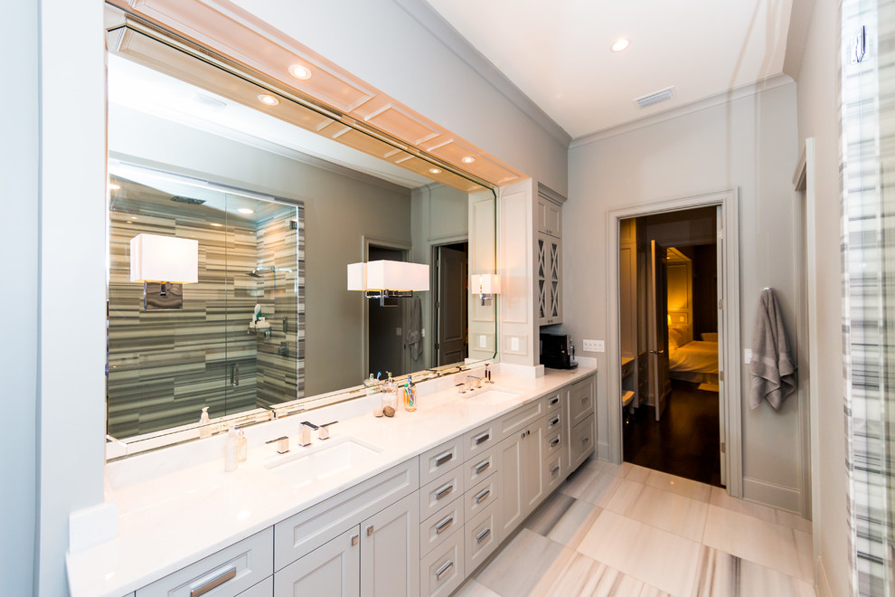 Photo of a large classic ensuite bathroom in Jacksonville with a submerged sink, flat-panel cabinets, grey cabinets, quartz worktops, a freestanding bath, an alcove shower, a two-piece toilet, white tiles, stone tiles, grey walls and medium hardwood flooring.