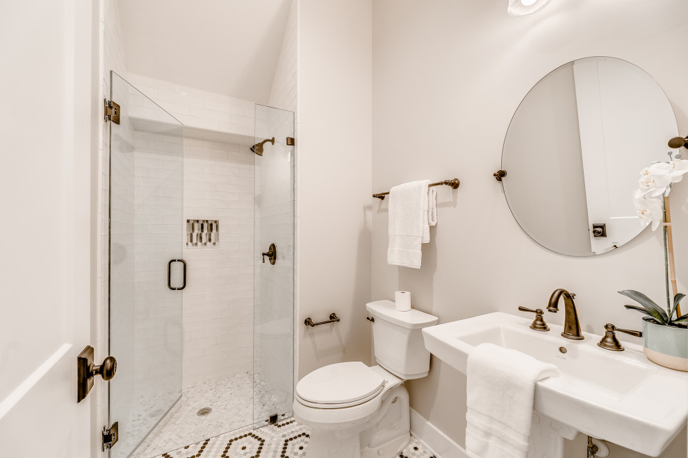 Идея дизайна: ванная комната среднего размера в стиле кантри с белыми фасадами, душем в нише, раздельным унитазом, белой плиткой, керамогранитной плиткой, серыми стенами, полом из цементной плитки, душевой кабиной, раковиной с пьедесталом, белым полом, душем с распашными дверями, белой столешницей, нишей и тумбой под одну раковину