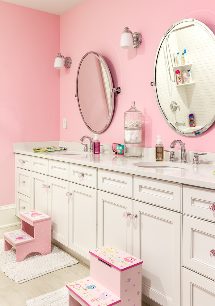 Example of a classic kids' bathroom design in New York with recessed-panel cabinets, white cabinets, pink walls and an undermount sink