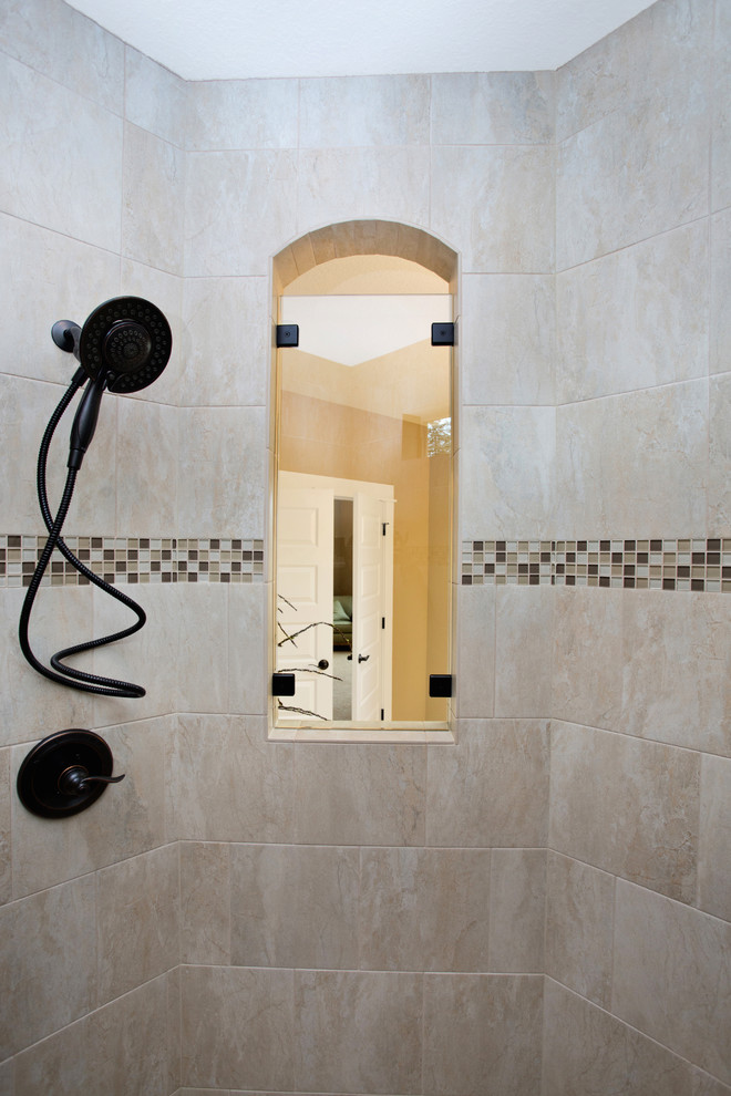 Modelo de cuarto de baño principal tradicional grande con armarios estilo shaker, puertas de armario de madera en tonos medios, ducha abierta, baldosas y/o azulejos grises, paredes beige, suelo de baldosas de cerámica y encimera de granito