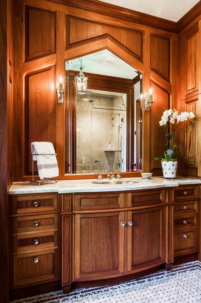 Réalisation d'une salle de bain tradition en bois brun avec un lavabo encastré et un placard avec porte à panneau encastré.