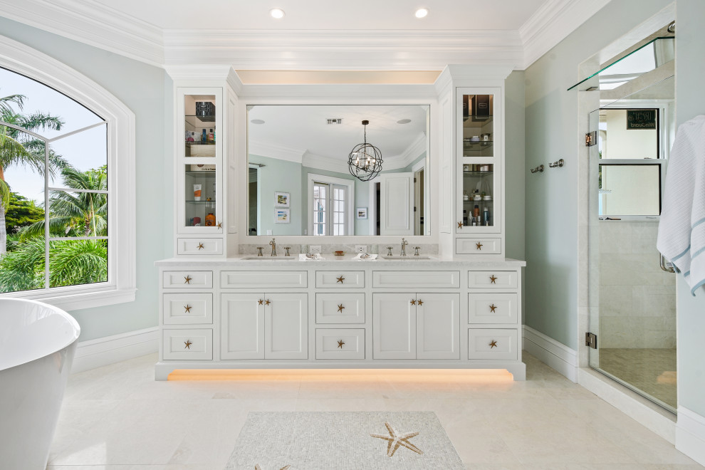 Diseño de cuarto de baño principal, doble y a medida tropical grande con armarios con rebordes decorativos, puertas de armario blancas, encimera de cuarcita y encimeras beige