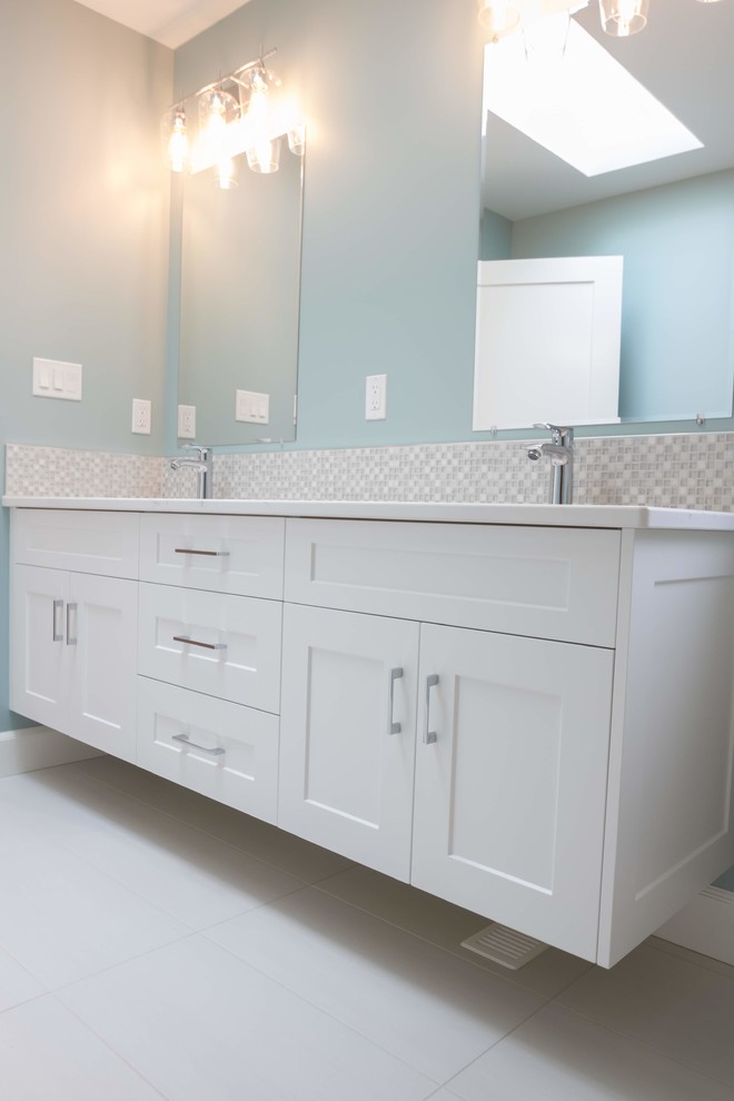Пример оригинального дизайна: главная ванная комната среднего размера в стиле кантри с фасадами с утопленной филенкой, белыми фасадами, двойным душем, унитазом-моноблоком, разноцветной плиткой, керамической плиткой, синими стенами, полом из керамогранита, врезной раковиной, столешницей из кварцита, белым полом, душем с распашными дверями и белой столешницей