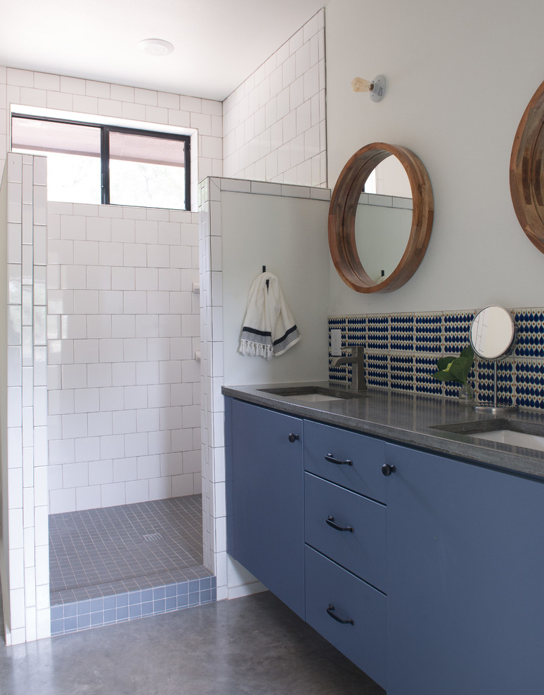 Стильный дизайн: ванная комната среднего размера в морском стиле с плоскими фасадами, синими фасадами, ванной в нише, душем над ванной, унитазом-моноблоком, белой плиткой, керамогранитной плиткой, белыми стенами, бетонным полом, душевой кабиной, врезной раковиной, столешницей из бетона и открытым душем - последний тренд