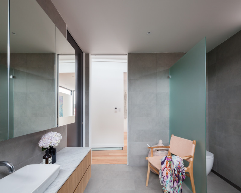 На фото: главная ванная комната среднего размера в современном стиле с фасадами островного типа, светлыми деревянными фасадами, унитазом-моноблоком, серой плиткой, керамической плиткой, серыми стенами, полом из керамической плитки, настольной раковиной и мраморной столешницей