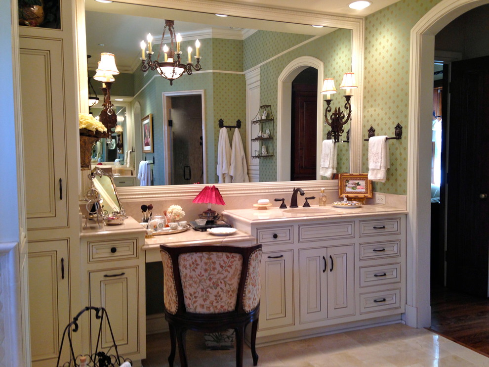 Cette image montre une grande salle de bain principale traditionnelle avec un lavabo encastré, un placard à porte affleurante, des portes de placard beiges, un plan de toilette en marbre, une douche d'angle, un carrelage beige, des dalles de pierre, un mur vert et un sol en marbre.