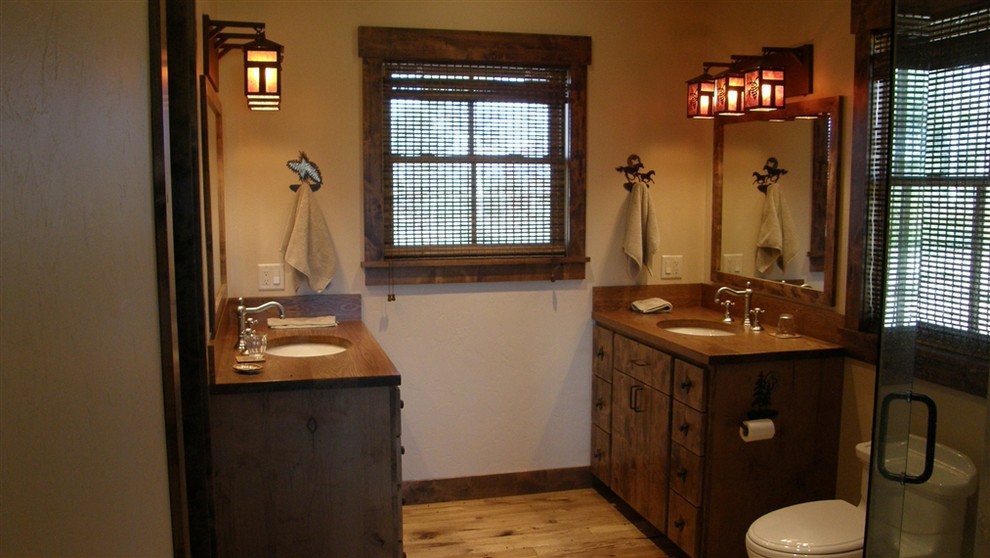 Photo of a medium sized rustic ensuite bathroom in Boise with flat-panel cabinets, dark wood cabinets, a corner shower, a one-piece toilet, white walls, light hardwood flooring, a submerged sink and wooden worktops.