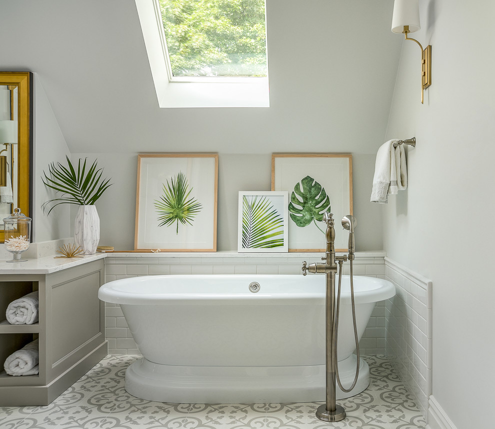 Bild på ett vintage badrum, med grå skåp, ett fristående badkar, vit kakel, tunnelbanekakel, grå väggar och cementgolv