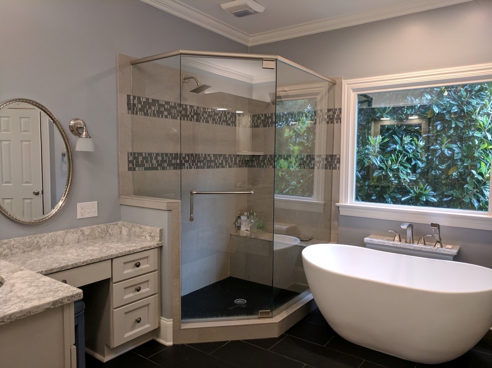 Klassisk inredning av ett badrum, med skåp i shakerstil, grå skåp, ett fristående badkar, en hörndusch, grå kakel, stenkakel, klinkergolv i porslin, ett undermonterad handfat, svart golv och dusch med gångjärnsdörr