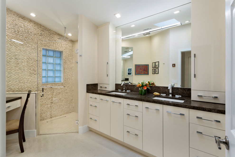 Пример оригинального дизайна: главная ванная комната среднего размера в современном стиле с плоскими фасадами, бежевыми фасадами, угловым душем, унитазом-моноблоком, бежевой плиткой, галечной плиткой, бежевыми стенами, полом из керамогранита, врезной раковиной, мраморной столешницей, бежевым полом, душем с распашными дверями и черной столешницей