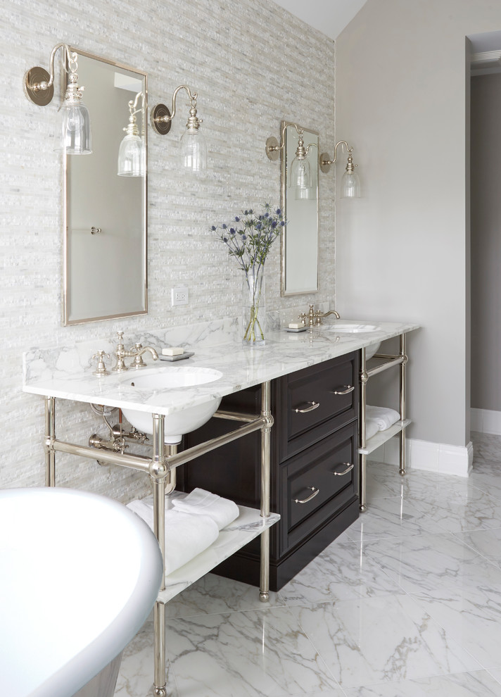 This is an example of a large contemporary ensuite bathroom in Chicago with raised-panel cabinets, dark wood cabinets, a freestanding bath, white tiles, marble tiles, white walls, marble flooring, a submerged sink, marble worktops and white floors.