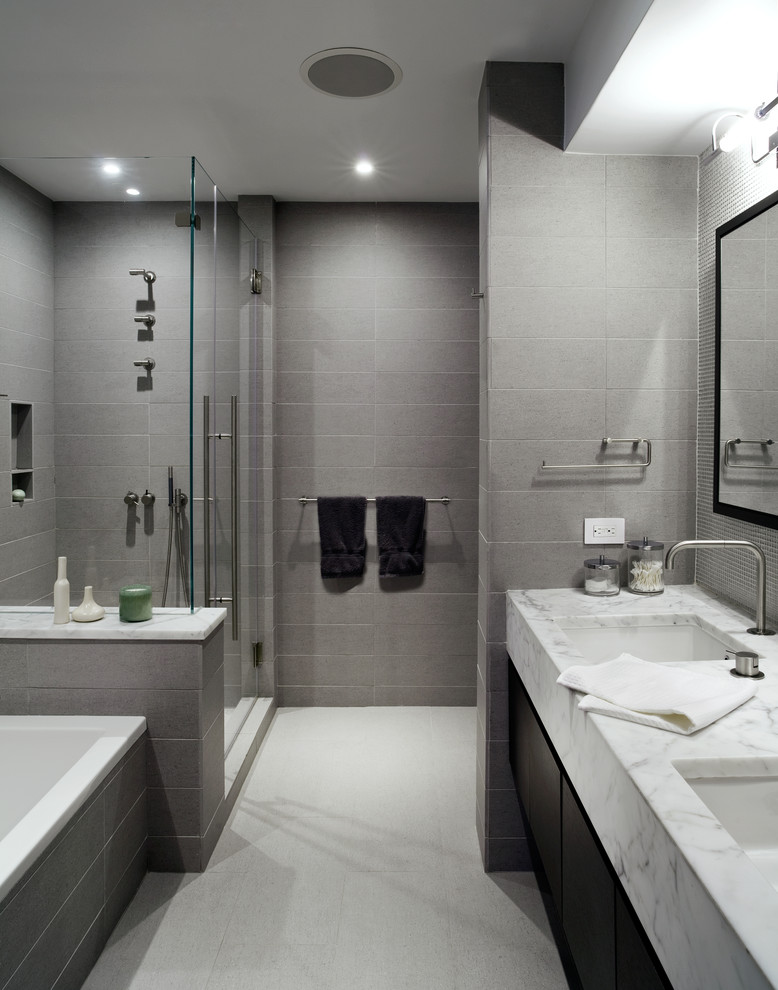 Modernes Badezimmer mit Marmor-Waschbecken/Waschtisch, grauen Fliesen, Unterbauwaschbecken, Einbaubadewanne, Duschnische, flächenbündigen Schrankfronten und dunklen Holzschränken in New York