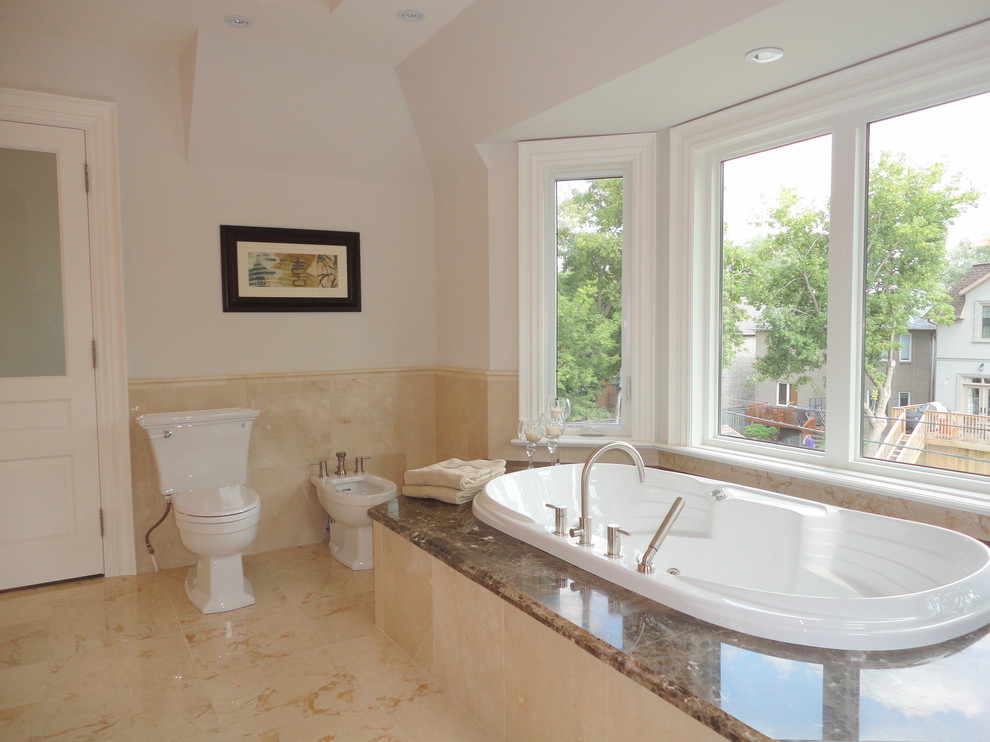 На фото: большая главная ванная комната в классическом стиле с врезной раковиной, фасадами с выступающей филенкой, белыми фасадами, столешницей из гранита, полновстраиваемой ванной, угловым душем, белыми стенами и полом из травертина