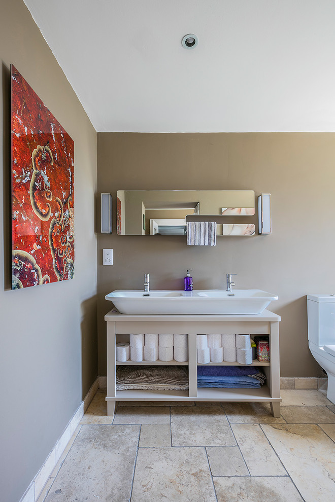 Modelo de cuarto de baño clásico renovado con sanitario de pared, baldosas y/o azulejos de mármol, lavabo suspendido, armarios abiertos, puertas de armario de madera clara, paredes beige y suelo beige