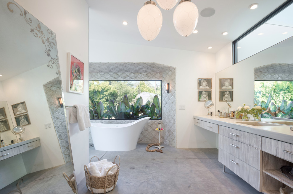 Exemple d'une grande salle de bain principale rétro en bois clair avec un placard à porte plane, un mur blanc, un lavabo intégré, une baignoire indépendante, un sol gris, sol en béton ciré et une fenêtre.