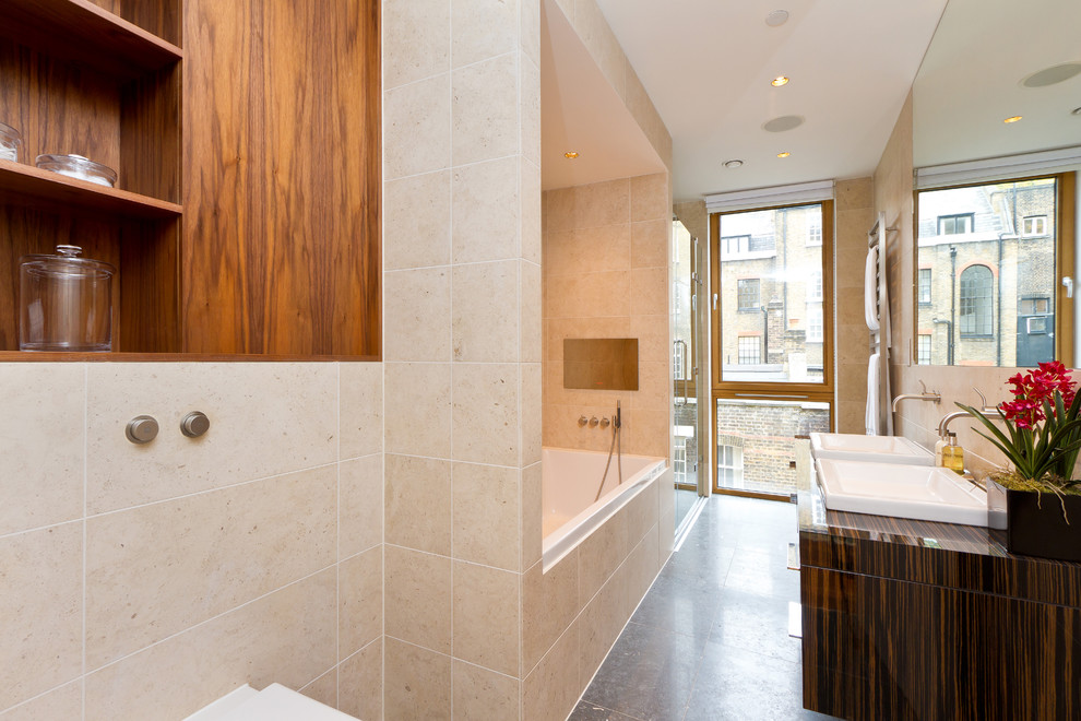 Foto de cuarto de baño contemporáneo con lavabo sobreencimera, armarios con paneles lisos, puertas de armario de madera en tonos medios, bañera encastrada, ducha empotrada y baldosas y/o azulejos beige