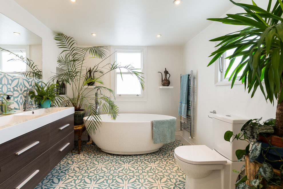 Idéer för ett modernt vit en-suite badrum, med släta luckor, skåp i mörkt trä, ett fristående badkar, en toalettstol med separat cisternkåpa, vita väggar, ett integrerad handfat och flerfärgat golv