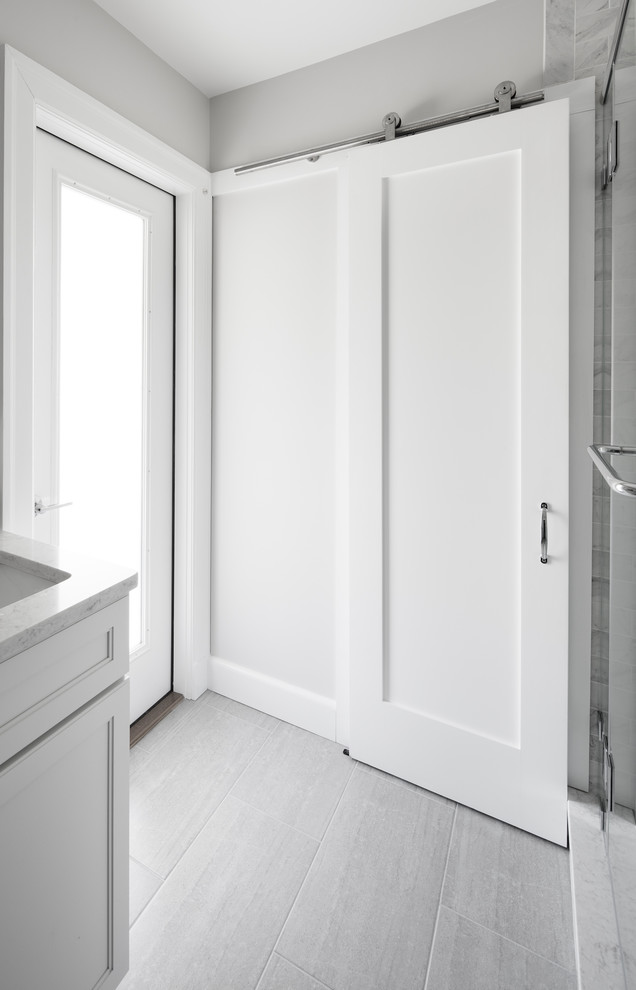 Klassisk inredning av ett mellanstort badrum med dusch, med skåp i shakerstil, vita skåp, en hörndusch, en toalettstol med separat cisternkåpa, grå kakel, vit kakel, marmorkakel, grå väggar, vinylgolv, ett undermonterad handfat, bänkskiva i kvartsit, grått golv och dusch med gångjärnsdörr