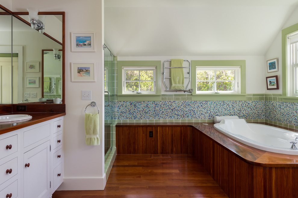 Foto på ett mellanstort maritimt en-suite badrum, med ett nedsänkt handfat, luckor med infälld panel, vita skåp, träbänkskiva, ett platsbyggt badkar, en dusch i en alkov, flerfärgad kakel, vita väggar, mörkt trägolv och mosaik