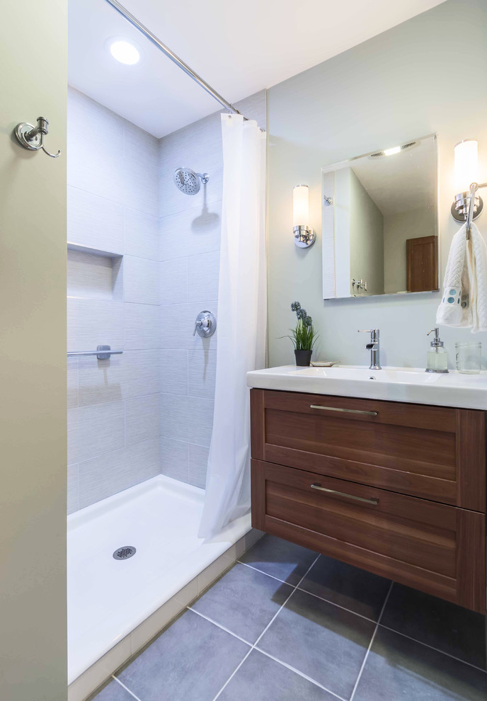 Modern inredning av ett litet vit vitt badrum med dusch, med skåp i shakerstil, skåp i mellenmörkt trä, en dusch i en alkov, en toalettstol med separat cisternkåpa, grå kakel, keramikplattor, grå väggar, klinkergolv i keramik, ett integrerad handfat, bänkskiva i akrylsten, grått golv och dusch med duschdraperi
