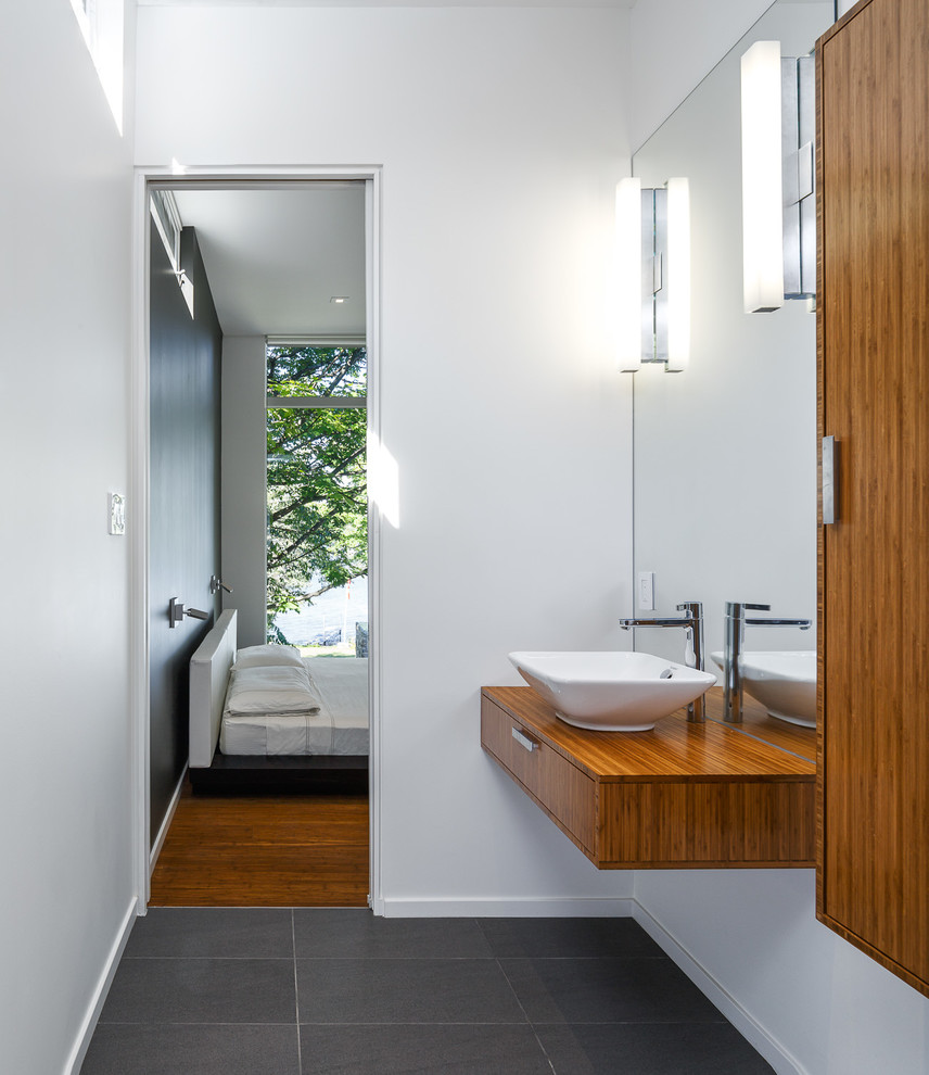 Idéer för att renovera ett funkis badrum, med ett fristående handfat, släta luckor, skåp i mellenmörkt trä, träbänkskiva och vita väggar