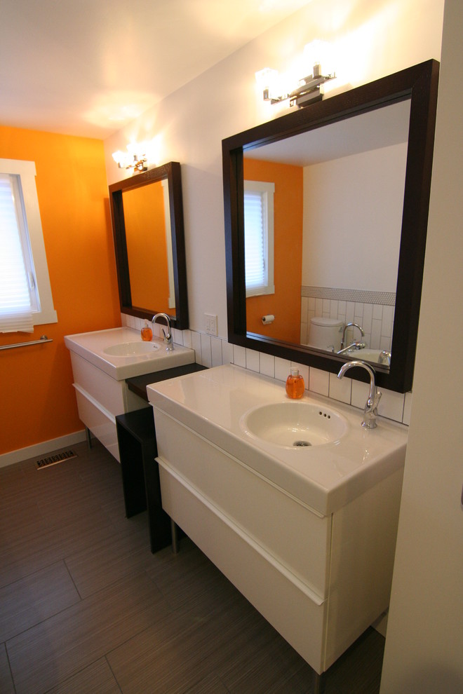 Modern inredning av ett mellanstort en-suite badrum, med ett integrerad handfat, släta luckor, vita skåp, ett fristående badkar, en hörndusch, en toalettstol med hel cisternkåpa, vit kakel, keramikplattor, orange väggar, vinylgolv, bänkskiva i kvarts, brunt golv och dusch med gångjärnsdörr
