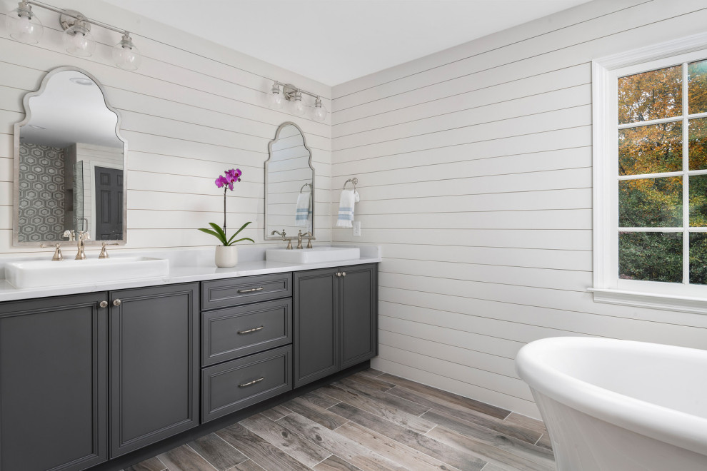 Inspiration för ett stort vintage vit vitt en-suite badrum, med luckor med profilerade fronter, grå skåp, ett fristående badkar, vita väggar, mellanmörkt trägolv, ett fristående handfat och grått golv