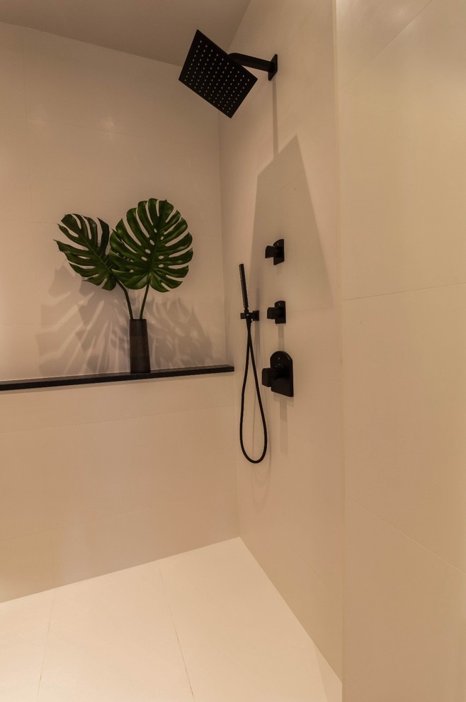 Пример оригинального дизайна: ванная комната в стиле модернизм с плоскими фасадами, белыми фасадами, накладной ванной, душем в нише, инсталляцией, белой плиткой, керамогранитной плиткой, белыми стенами, полом из керамогранита, врезной раковиной, столешницей из нержавеющей стали, белым полом, открытым душем и черной столешницей