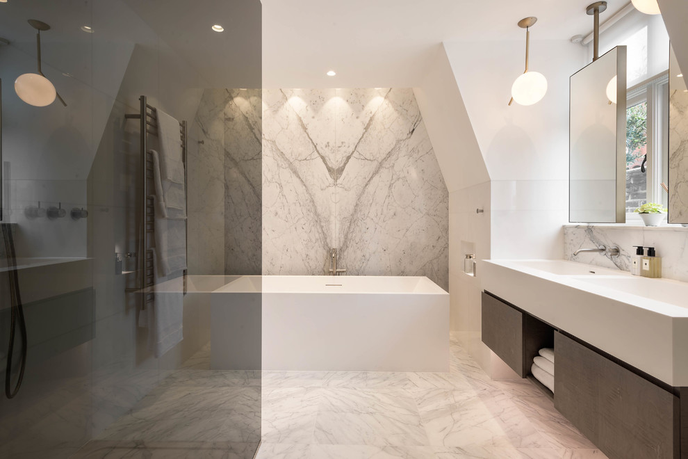Medium sized contemporary bathroom in London with flat-panel cabinets, light wood cabinets, a freestanding bath, a walk-in shower, a wall mounted toilet, beige tiles, marble tiles, beige walls, marble flooring, a trough sink, beige floors and an open shower.