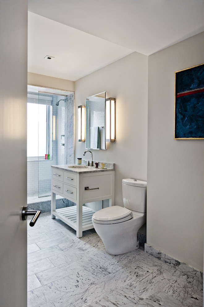 Photo of a medium sized contemporary ensuite bathroom in New York with flat-panel cabinets, white cabinets, an alcove shower, a two-piece toilet, metro tiles, beige walls, a submerged sink, marble worktops, white tiles and marble flooring.