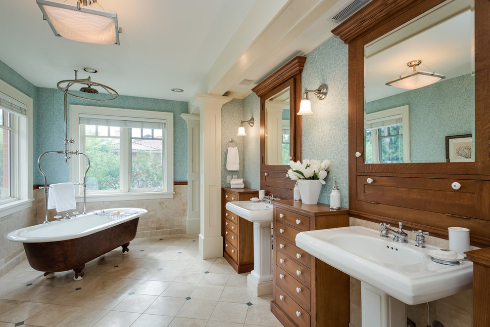 Inredning av ett klassiskt badrum, med skåp i mellenmörkt trä, ett badkar med tassar, en dusch/badkar-kombination, flerfärgade väggar, ett piedestal handfat, flerfärgat golv och släta luckor
