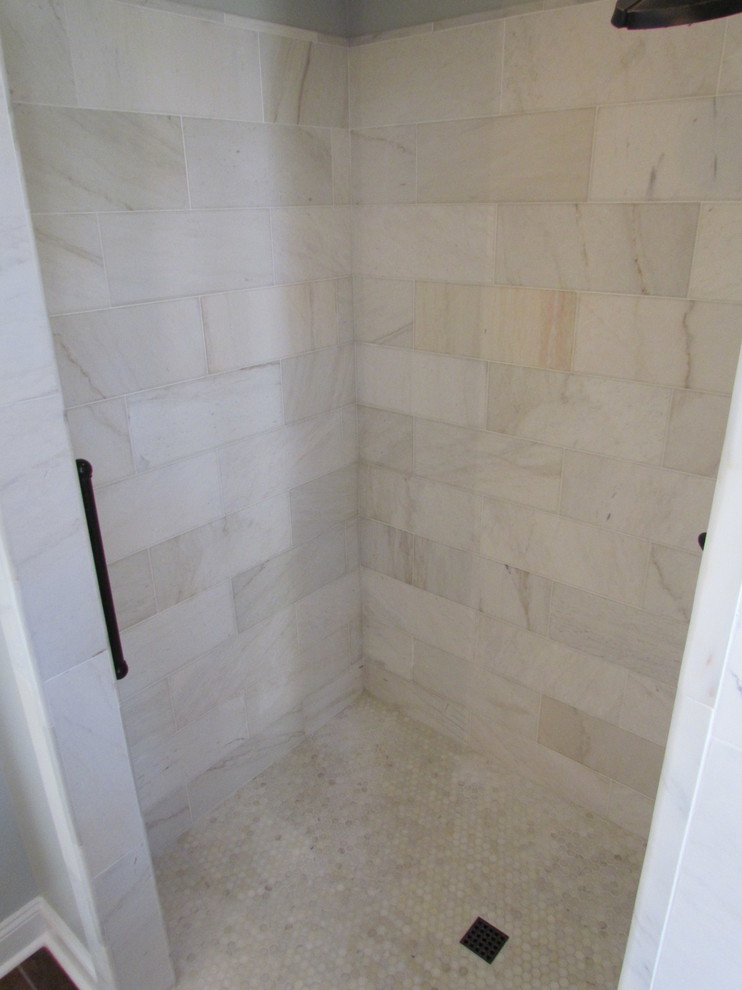 Medium sized traditional ensuite bathroom in Raleigh with an alcove shower, a two-piece toilet, grey tiles, grey walls, laminate floors, brown floors and a hinged door.