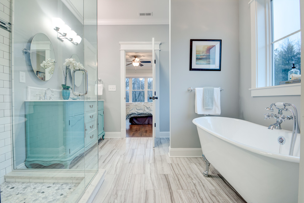 Inredning av ett amerikanskt stort en-suite badrum, med möbel-liknande, blå skåp, ett badkar med tassar, en hörndusch, porslinskakel, grå väggar, klinkergolv i porslin, ett undermonterad handfat och marmorbänkskiva