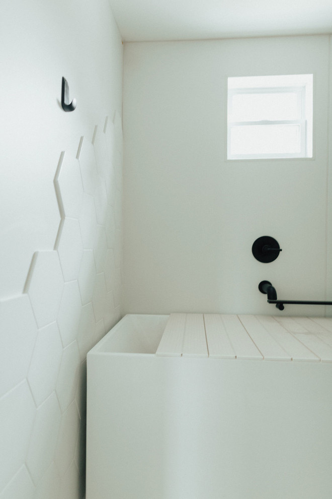 Cette image montre une salle de bain principale minimaliste de taille moyenne avec un placard à porte plane, des portes de placard blanches, un bain japonais, un combiné douche/baignoire, un carrelage blanc, des carreaux de porcelaine, un mur blanc, un sol en vinyl, un lavabo intégré, un plan de toilette en surface solide, un sol gris, aucune cabine et un plan de toilette blanc.