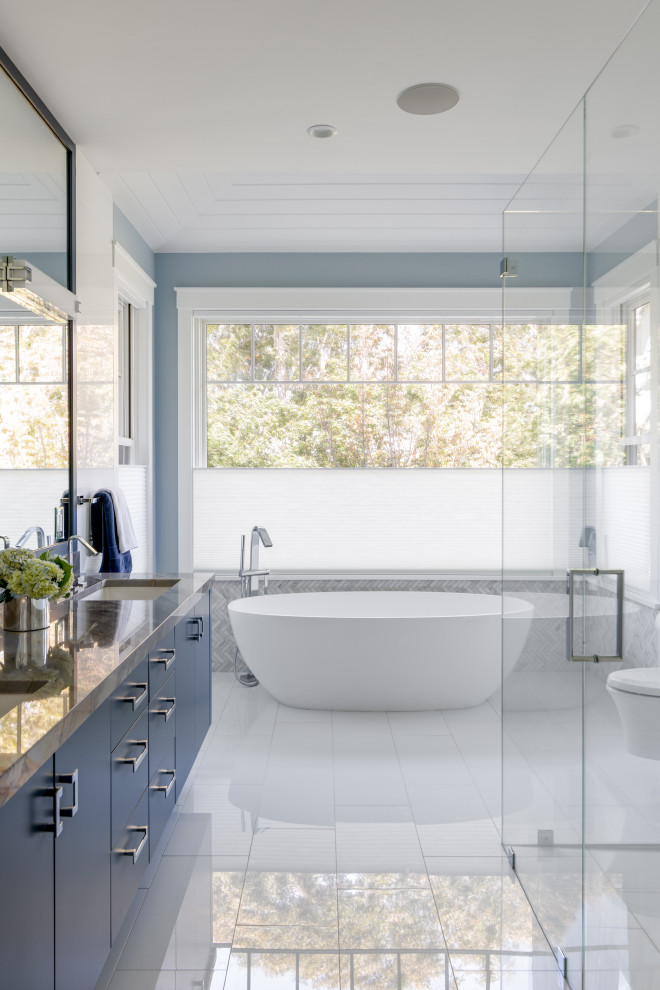 Design ideas for a beach style bathroom in Boston with flat-panel cabinets, blue cabinets, a freestanding bath, a built-in shower, grey tiles, mosaic tiles, blue walls, a submerged sink, white floors, grey worktops, double sinks and a floating vanity unit.