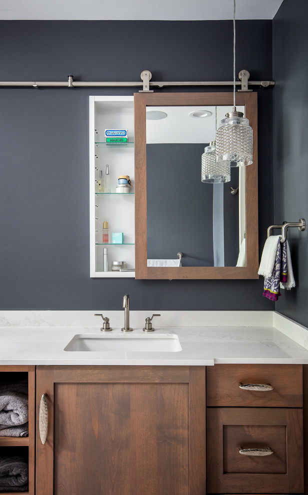 Immagine di una stanza da bagno tradizionale con ante in stile shaker, ante in legno bruno, pareti nere, lavabo sottopiano e top bianco