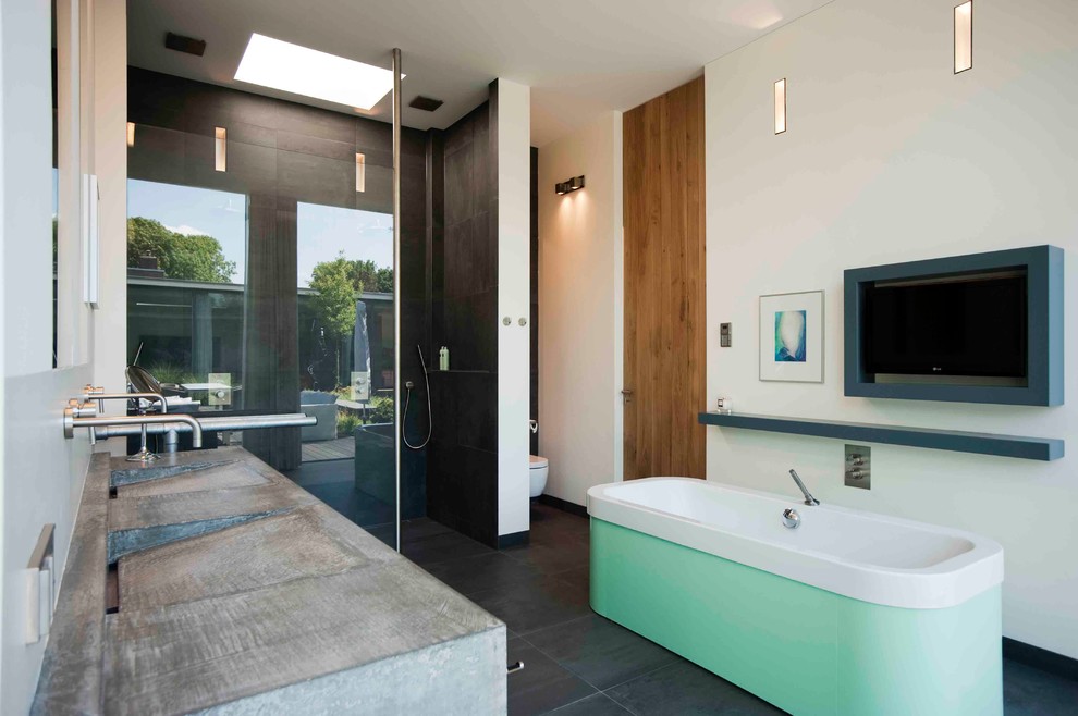 Inspiration for a large contemporary master gray tile ceramic tile bathroom remodel in New York with concrete countertops, a wall-mount toilet, a trough sink, flat-panel cabinets, green cabinets and white walls