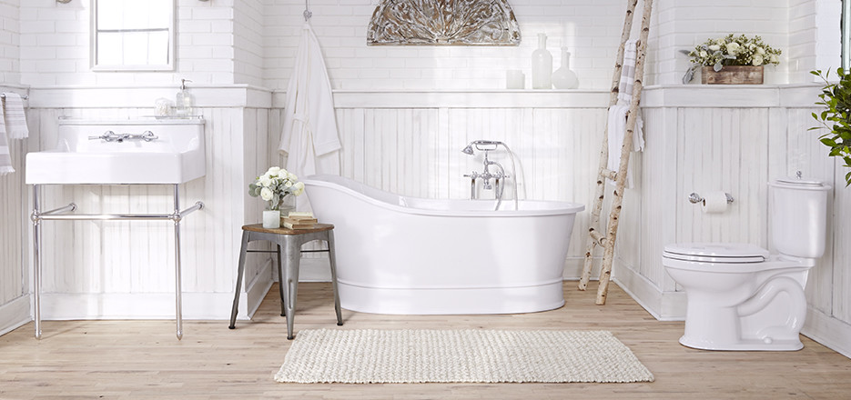 Cette photo montre une salle de bain principale nature de taille moyenne avec une baignoire indépendante, WC séparés, un mur blanc, parquet clair, un plan vasque et un sol marron.