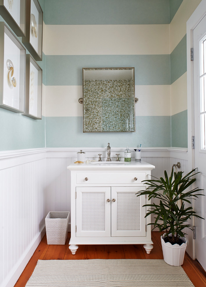 Coastal bathroom in New York with a submerged sink, marble worktops, white cabinets, multi-coloured walls, medium hardwood flooring and recessed-panel cabinets.