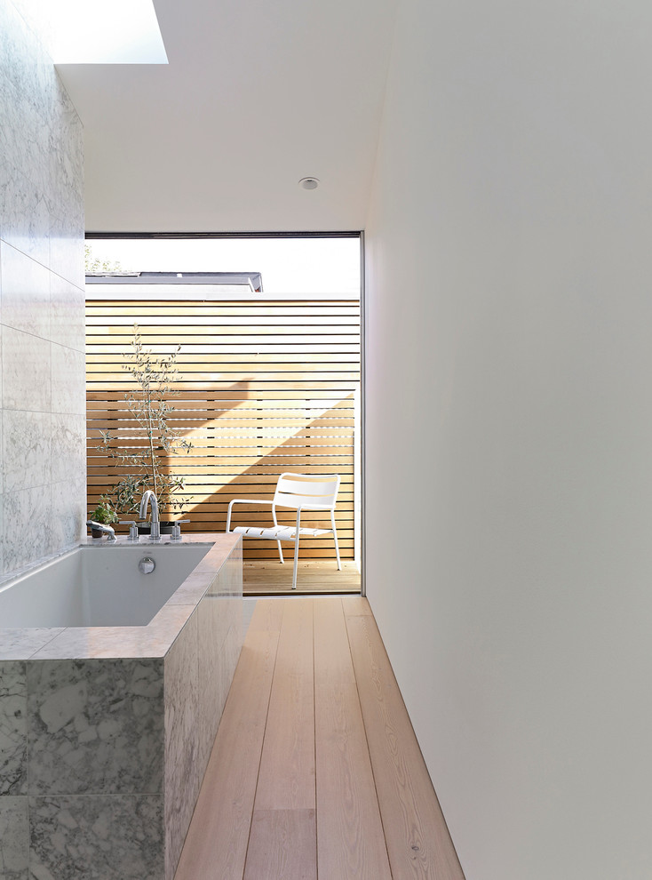 Idée de décoration pour une salle de bain minimaliste avec une baignoire encastrée, un mur blanc et parquet clair.