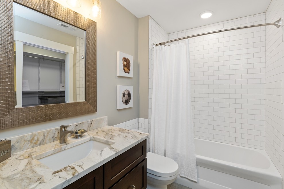 Bathroom - mid-sized kids' white tile and ceramic tile bathroom idea in Cincinnati with shaker cabinets, brown cabinets, a two-piece toilet, gray walls, an undermount sink, granite countertops and beige countertops