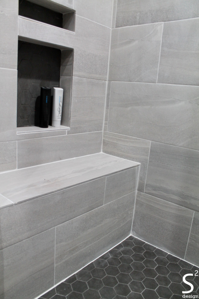 Photo of a medium sized modern ensuite bathroom in Houston with flat-panel cabinets, medium wood cabinets, an alcove bath, an alcove shower, a two-piece toilet, grey tiles, porcelain tiles, grey walls, porcelain flooring, a submerged sink, granite worktops, grey floors, a shower curtain, black worktops, a shower bench, double sinks and a built in vanity unit.