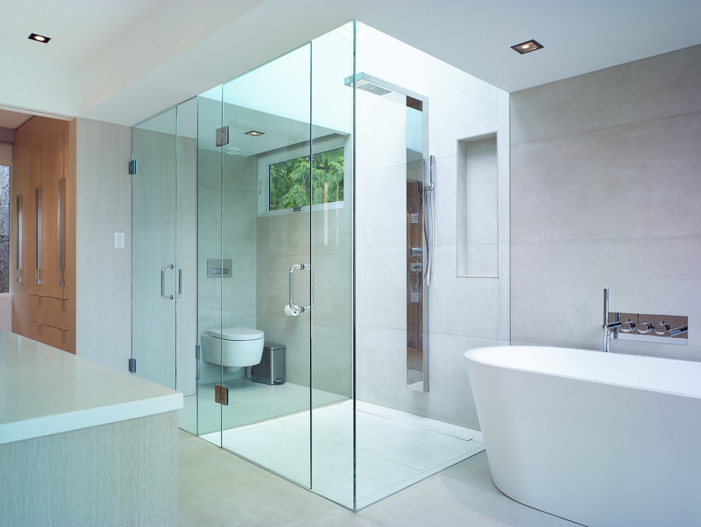 Example of a large trendy master beige tile and porcelain tile porcelain tile and beige floor bathroom design in Vancouver with flat-panel cabinets, light wood cabinets, a wall-mount toilet, beige walls, a drop-in sink, quartz countertops and a hinged shower door