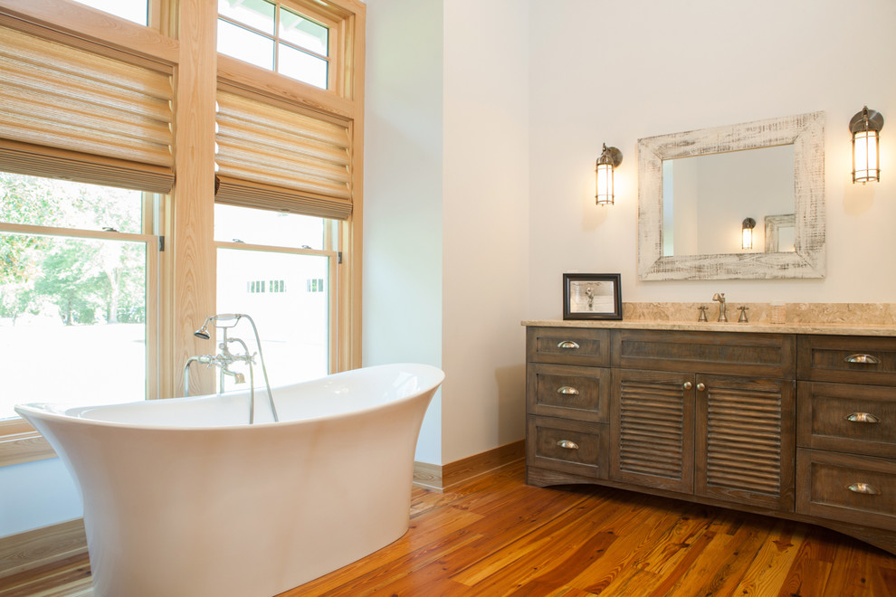Example of a mid-sized beach style master light wood floor freestanding bathtub design in Other with furniture-like cabinets, dark wood cabinets, white walls and granite countertops
