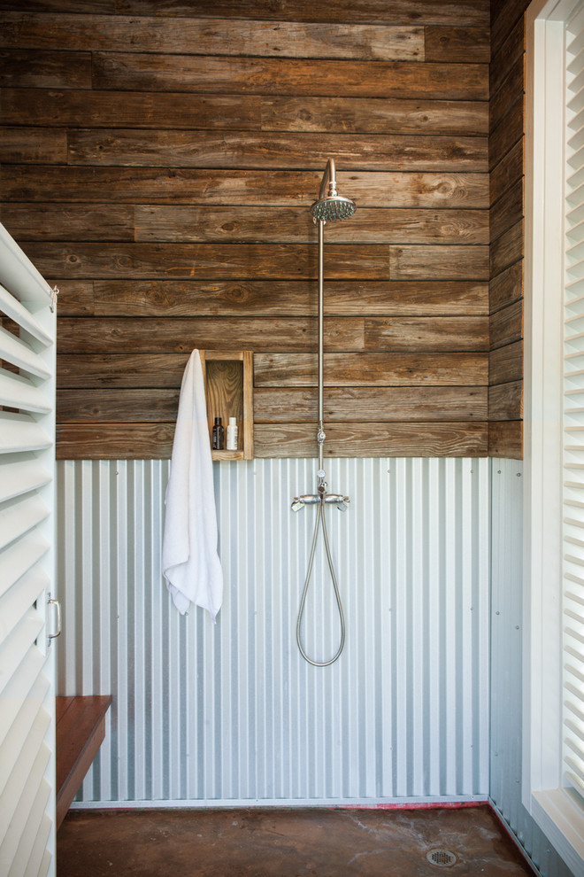 Cette image montre une petite salle de bain marine en bois foncé avec une douche ouverte, sol en béton ciré, une cabine de douche à porte battante et une fenêtre.
