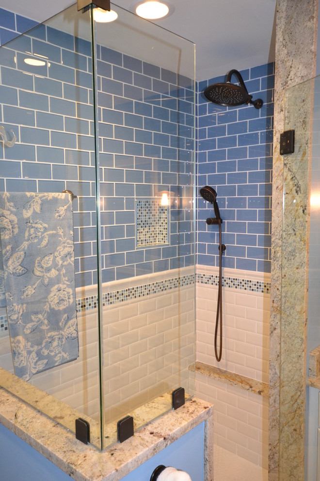 Exempel på ett maritimt en-suite badrum, med ett undermonterad handfat, luckor med infälld panel, vita skåp, granitbänkskiva, en dusch i en alkov, en toalettstol med separat cisternkåpa, blå kakel, glaskakel, blå väggar och klinkergolv i porslin