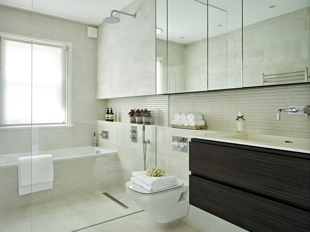 Bild på ett mellanstort funkis vit vitt badrum, med släta luckor, skåp i mörkt trä, en vägghängd toalettstol, grå kakel, porslinskakel, klinkergolv i porslin, grått golv, med dusch som är öppen, ett badkar i en alkov, våtrum och ett integrerad handfat